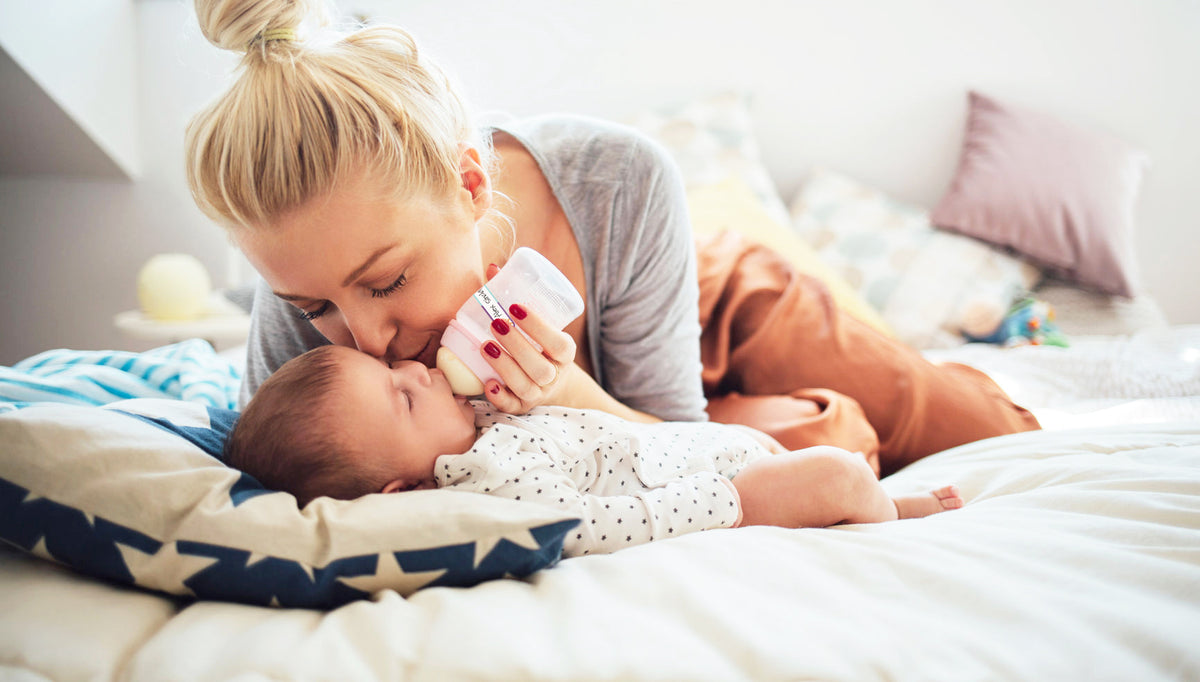 mom feeding baby bottle with label